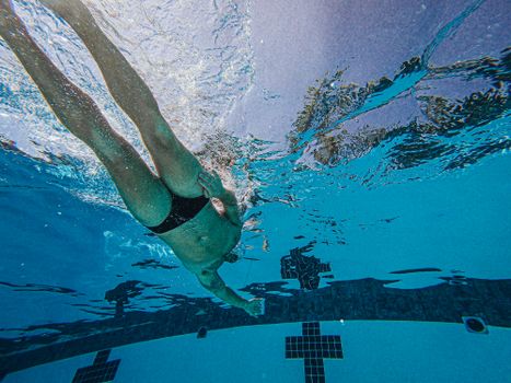 Underwater view of a male swimmer training in a pool, showcasing athleticism.