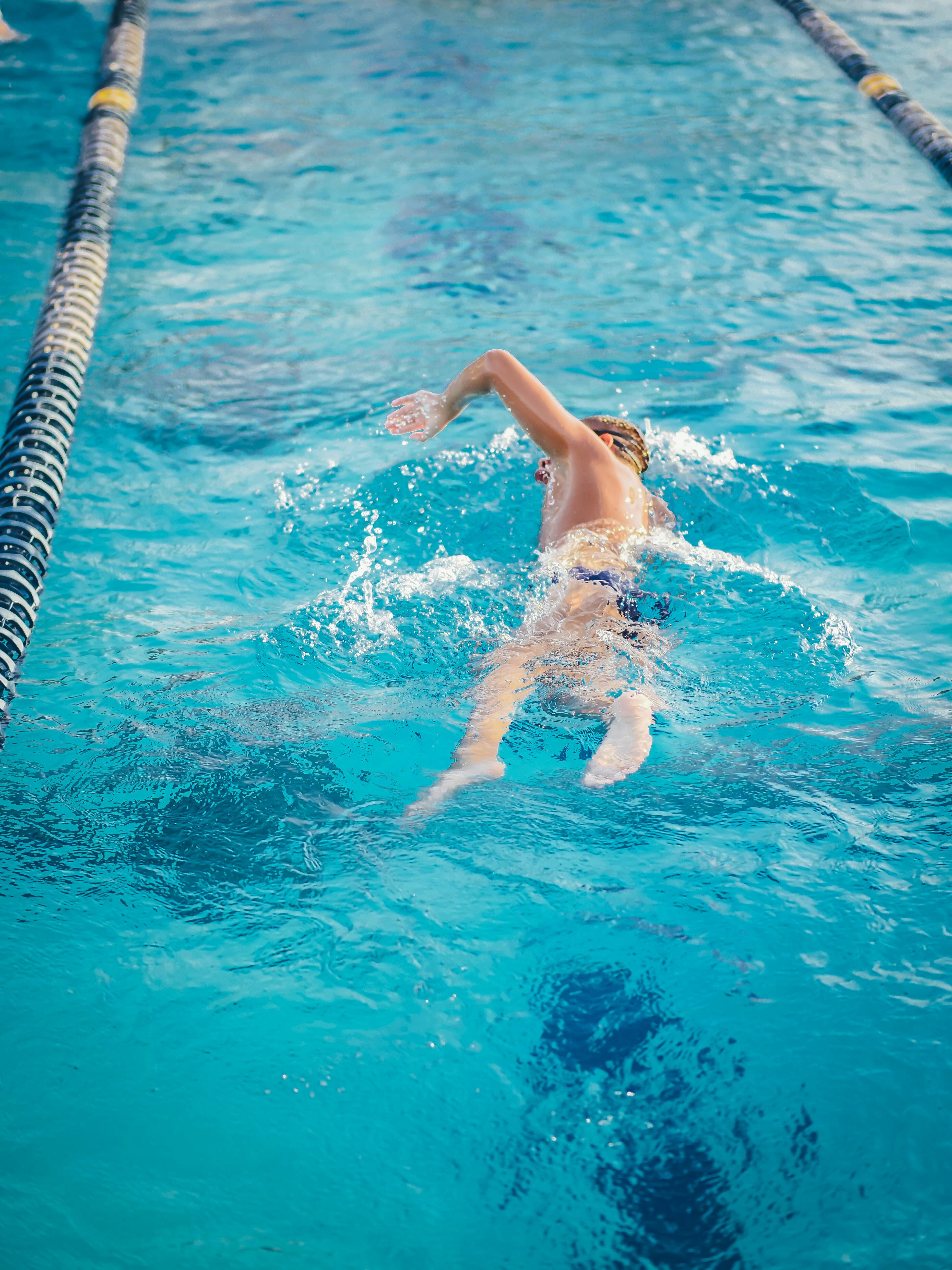 a man in swimming trunks swimming in the pool