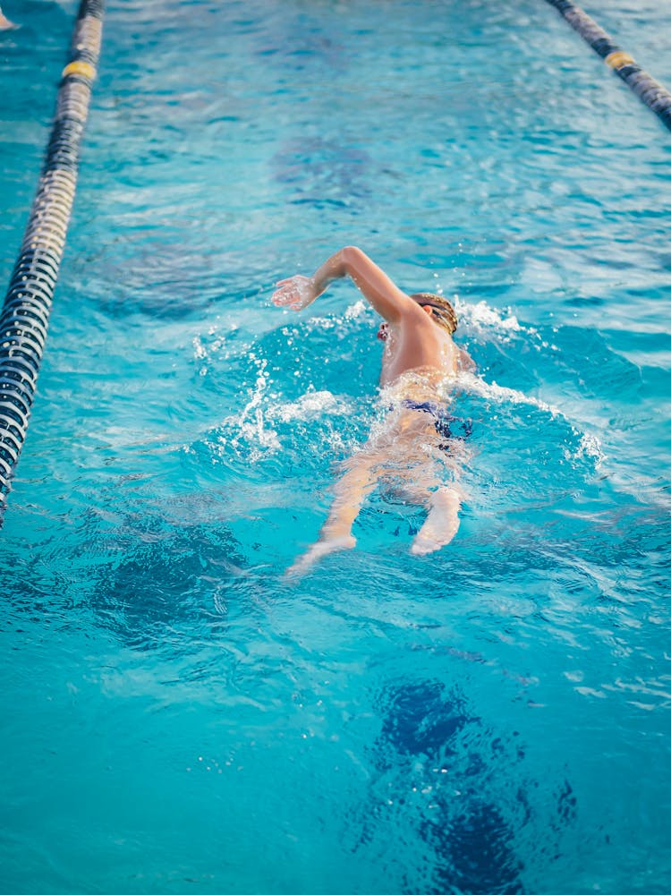 A Man In Swimming Trunks Swimming In The Pool