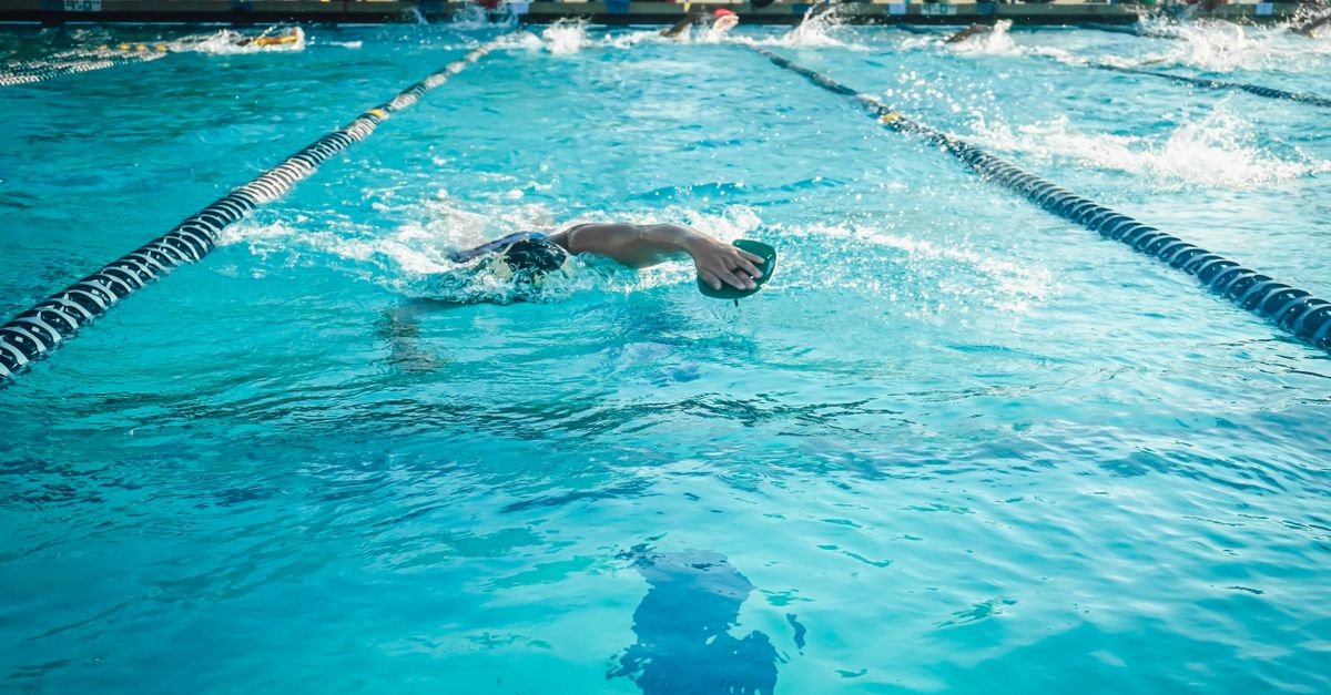 An adult swimmer practicing freestyle in an outdoor Olympic-size pool.