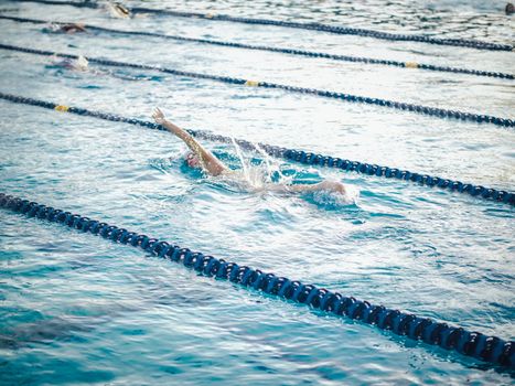 Swimmer practicing freestyle stroke in a lap pool, focused on training and technique.