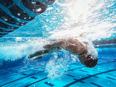 Dynamic underwater view of a man swimming freestyle in a clear blue pool.