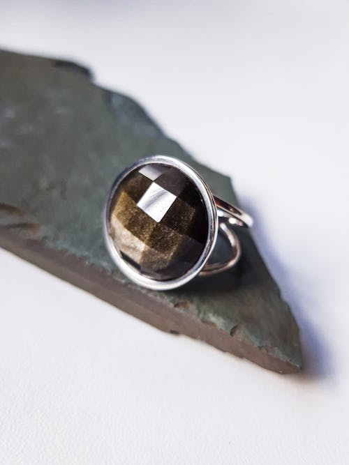 From above of creative design of silver ring with semiprecious stone on rock piece on light background