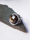 From above of creative design of silver ring with semiprecious stone on rock piece on light background