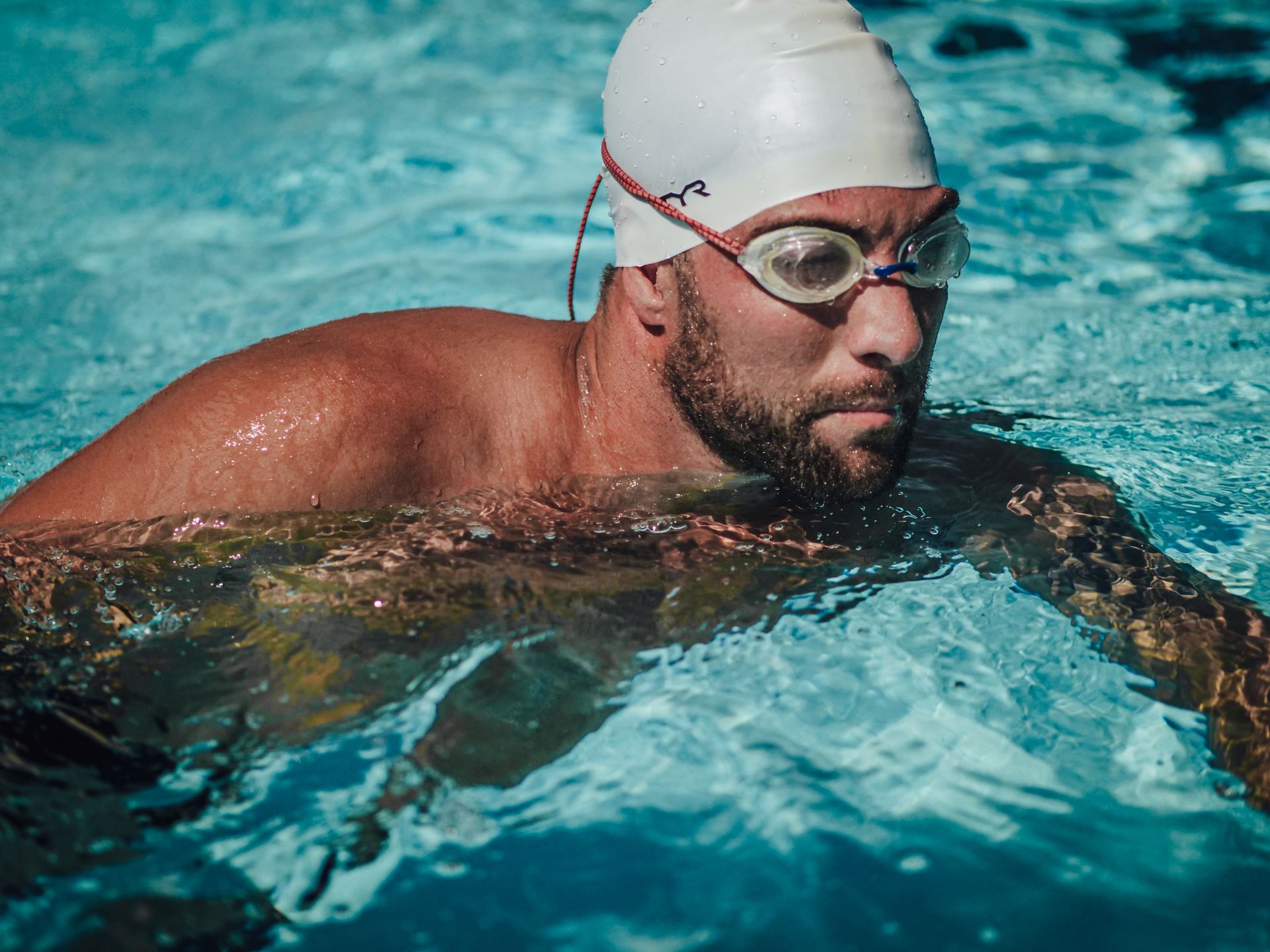 Man in Swimming Goggles and Water Cap while Swimming on the Pool