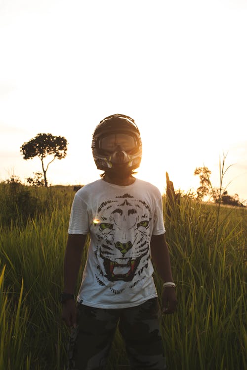 Man in Black Full Face Helmet Standing on Green Grass during Daytime