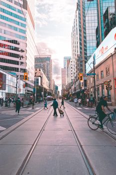 Busy downtown Toronto street scene with people and traffic amidst tall skyscrapers during daytime.
