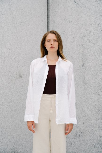 Elegant young woman standing against a minimalist backdrop, showcasing modern fashion.