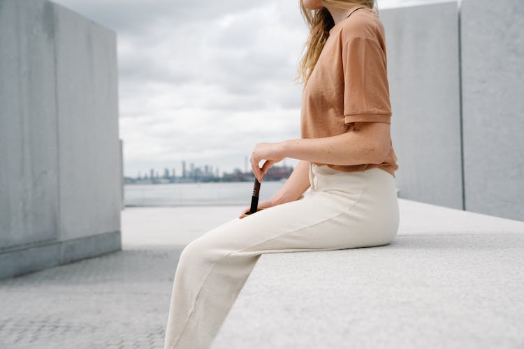 Woman In Brown T Shirt Sitting On A Concrete Railing