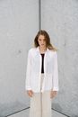 Woman in White Blazer Standing Beside White Wall