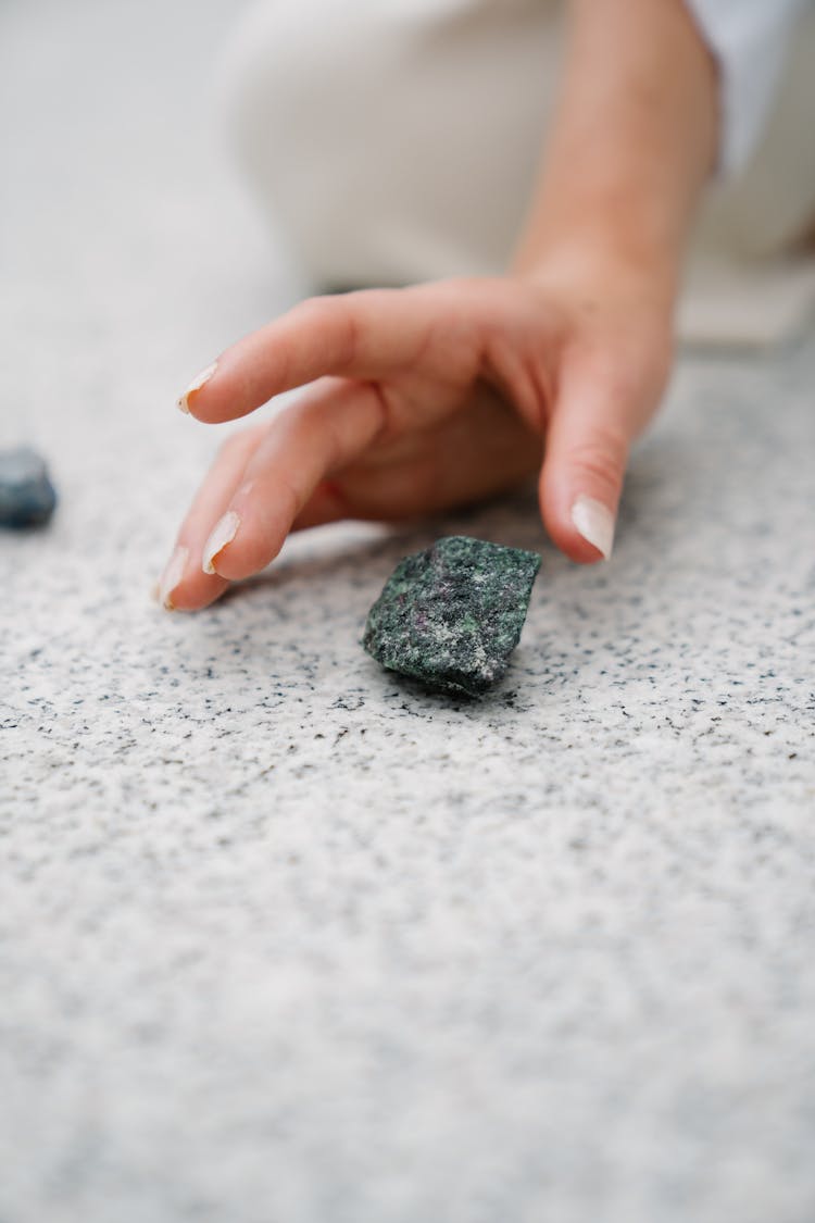 A Hand Getting The Gray Stone On The Ground