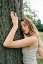 Woman in White Tank Top Leaning on Tree