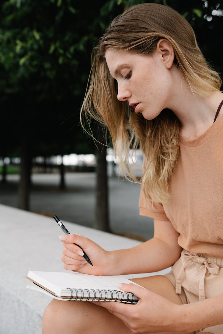 Woman In Brown T Shirt Writing On A Notebook