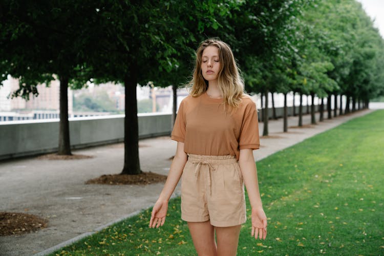 Woman In Brown T Shirt And Shorts Standing On Green Grass