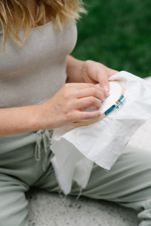 Free A close-up shot of a woman doing embroidery outdoors, focusing on her hands. Stock Photo