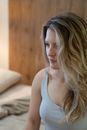 Woman in Tank Top Sitting on the Bed while Looking Afar
