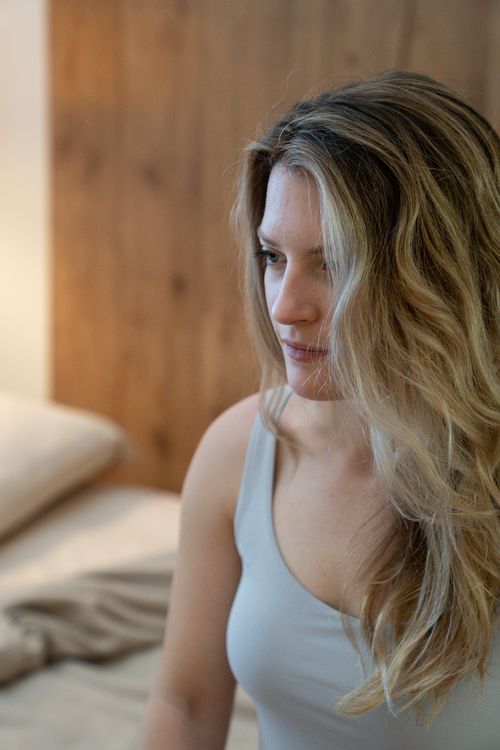 Free Close-up profile of a woman in a tank top, sitting indoors with a contemplative expression. Stock Photo