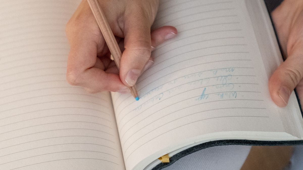 罫線のノートに鉛筆で書き込む手元(イメージ)