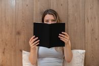 Woman in Gray Shirt Holding a Black Book