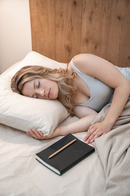 Free Woman in Gray Tank Top Lying on Bed Stock Photo