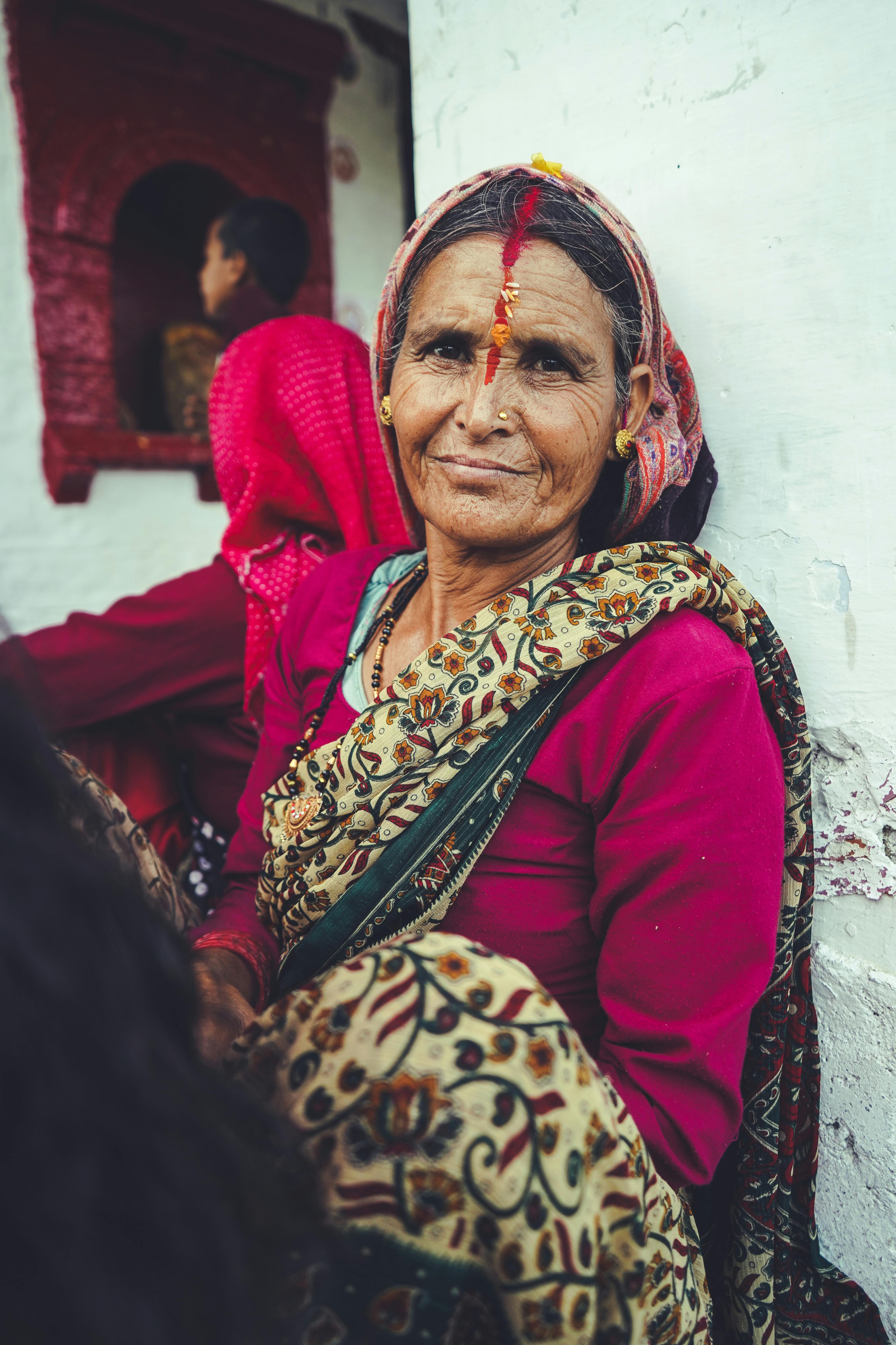 Portrait of an elderly Indian woman in traditional clothing, smiling at the camera.