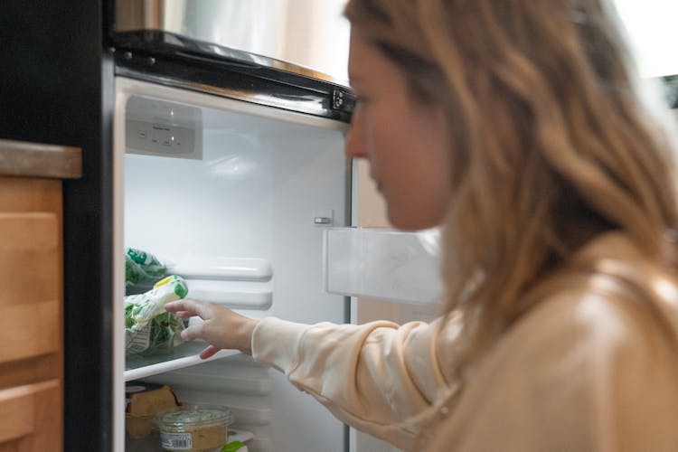 Woman In Brown Long Sleeve Shirt Looking In The Refrigerator