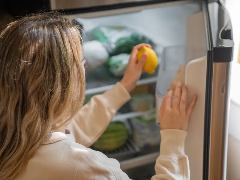 Woman taking a lemon out of a refrigerator Woman taking a lemon out of a refrigerator
