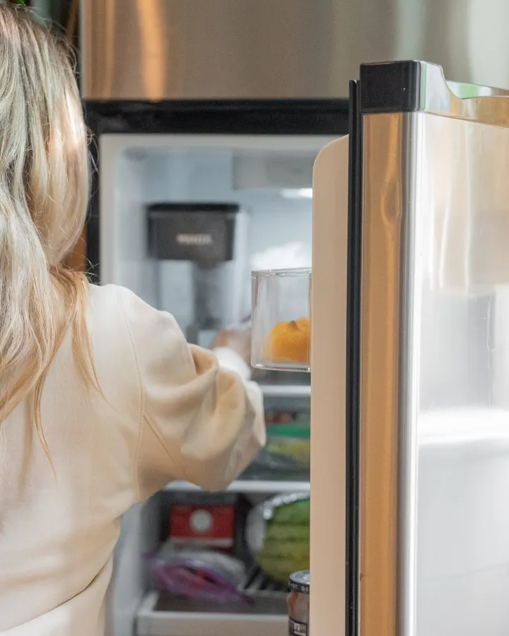 Noisy Refrigerator Repair in La Mesa, CA Woman getting food from a refrigerator in a bright kitchen that is making loud noises