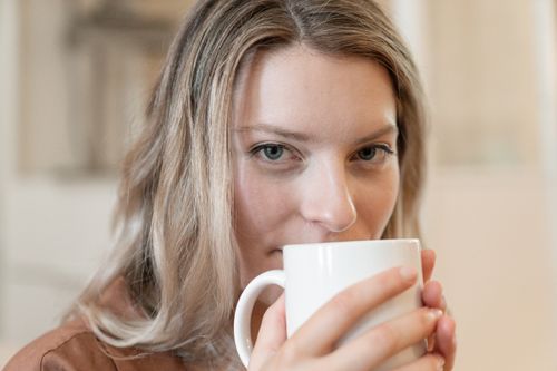 Free Close-up of a young woman enjoying a warm drink indoors, promoting relaxation. Stock Photo