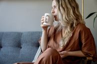 Woman in Brown Long Sleeve Shirt Holding White Ceramic Mug