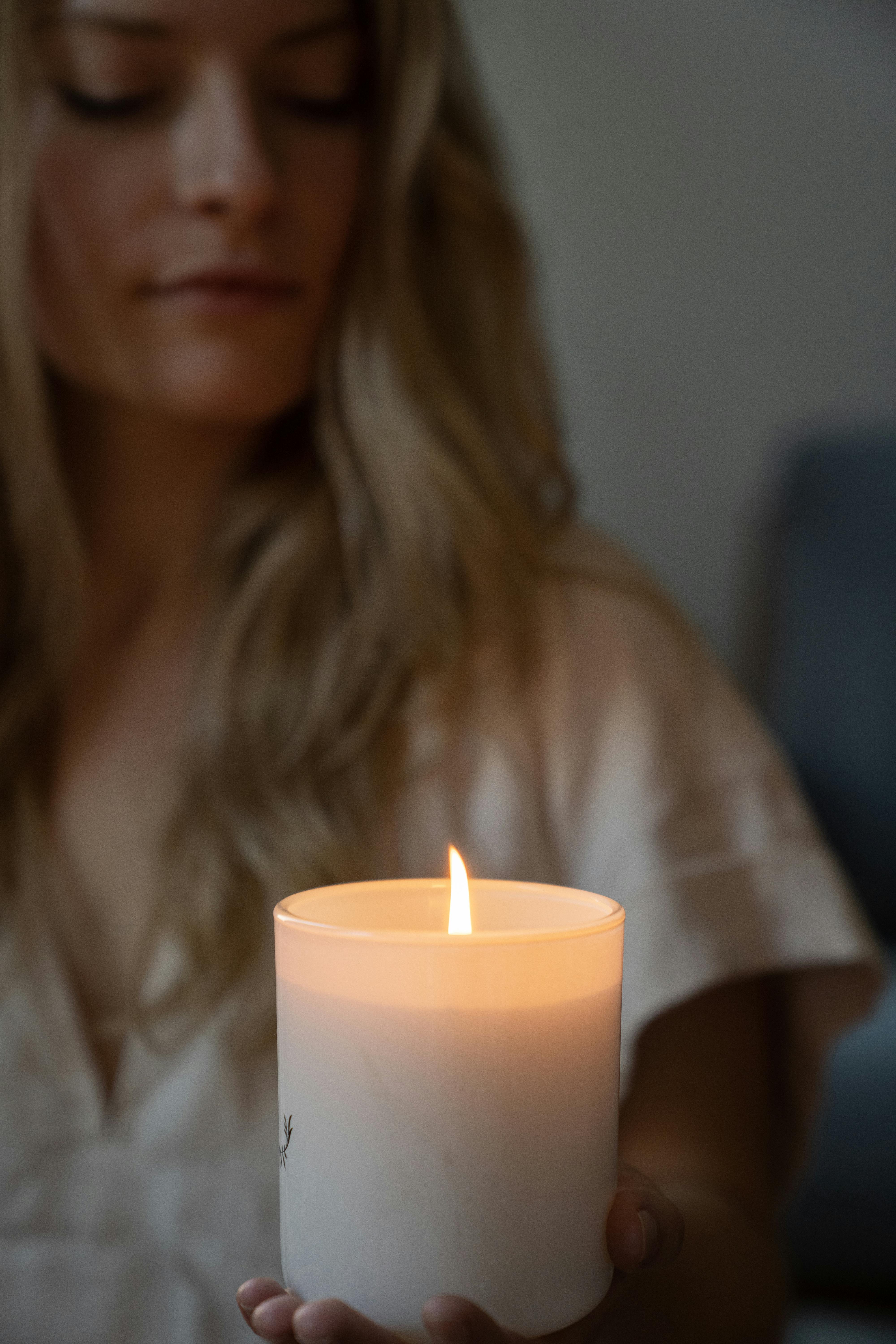 A close-up of a woman holding a glowing candle, creating a calm ambiance.