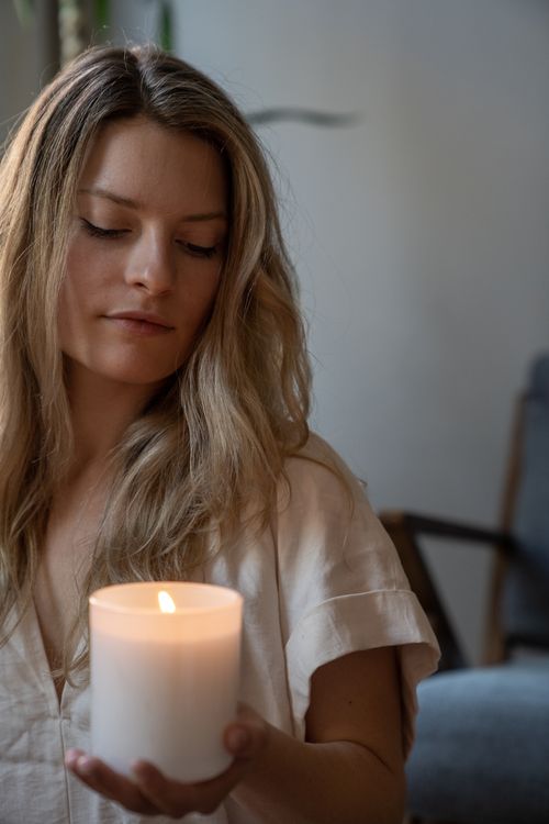 Free A calm woman with long hair holds a lit candle indoors, embracing tranquility. Stock Photo
