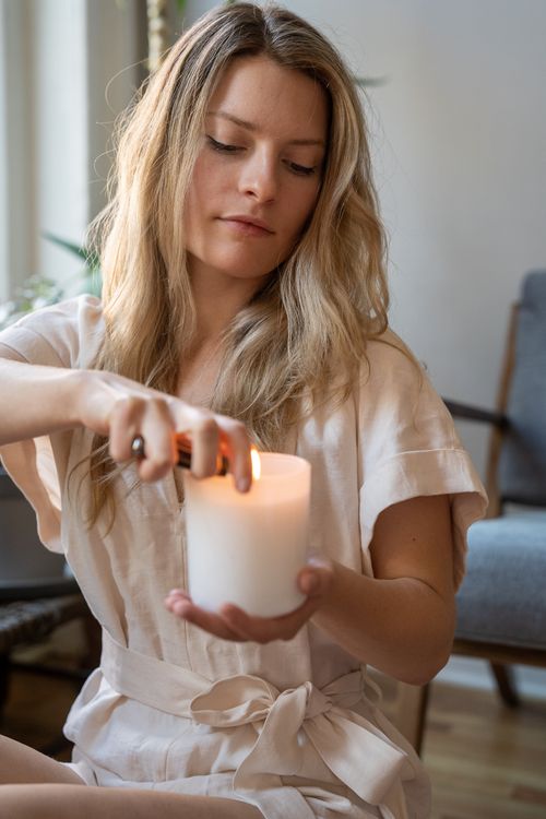 Free A serene moment capturing a woman lighting a candle indoors, exuding warmth and tranquility. Stock Photo
