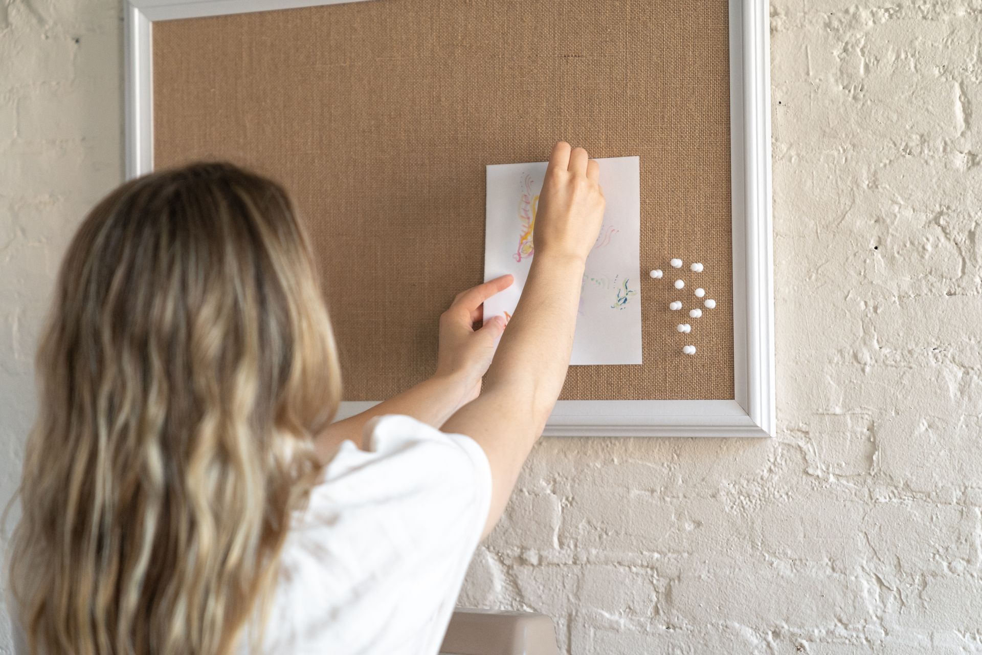 A Woman Posting an Artwork on the Board