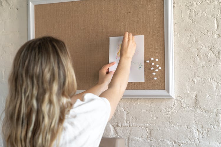 A Woman Posting An Artwork On The Board