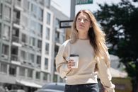 Woman in Beige Long Sleeve Shirt Holding White Cup