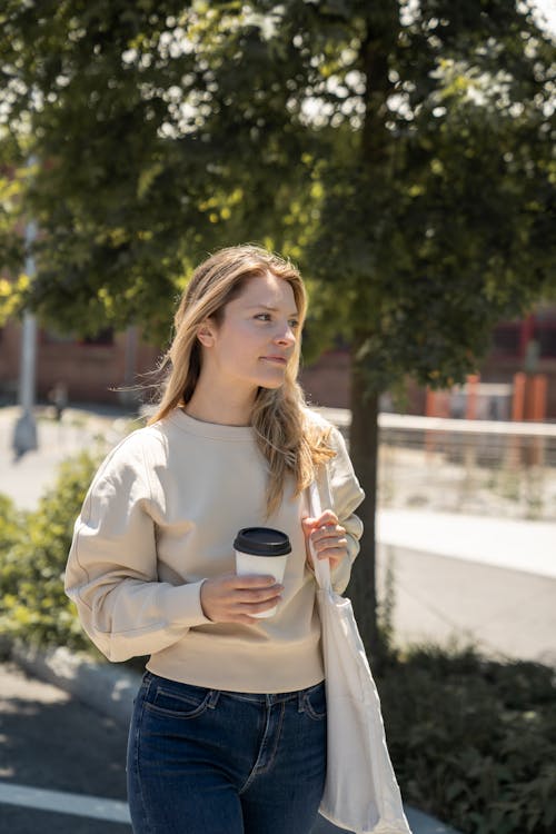 Woman in Cream Long Sleeves Holding a Paper Cup · Free Stock Photo