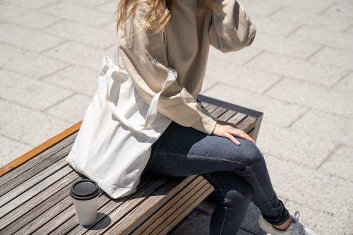 Close-Up Shot of a Person Sitting on Wooden Bench 