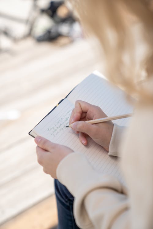 Free A Person Writing on a Journal Stock Photo