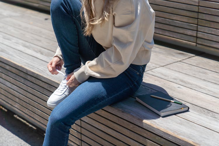 Woman Sitting On Bench And Tie Shoelaces