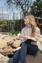 Woman Holding a Pen and Notebook While Sitting on Rock