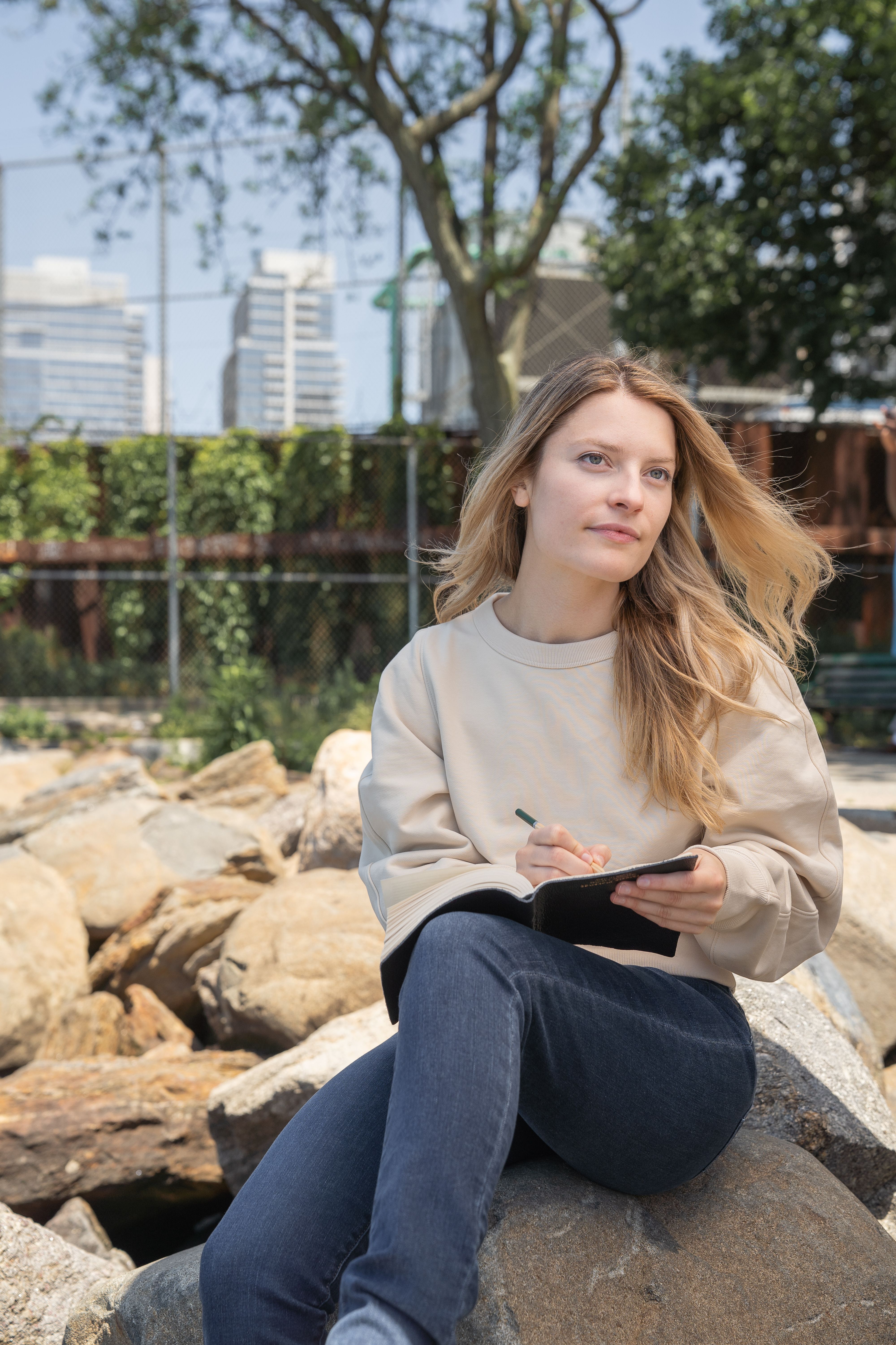 Woman Sitting on a Rock Writing on Her Notebook · Free Stock Photo