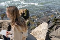 Woman Sitting on Rock Near Body of Water