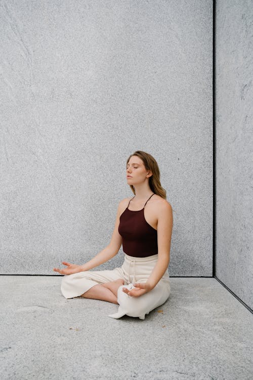 Woman Meditating on Concrete Pavement