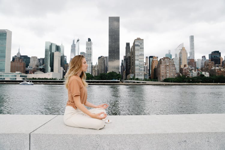 A Woman Meditating Near A Body Of Water