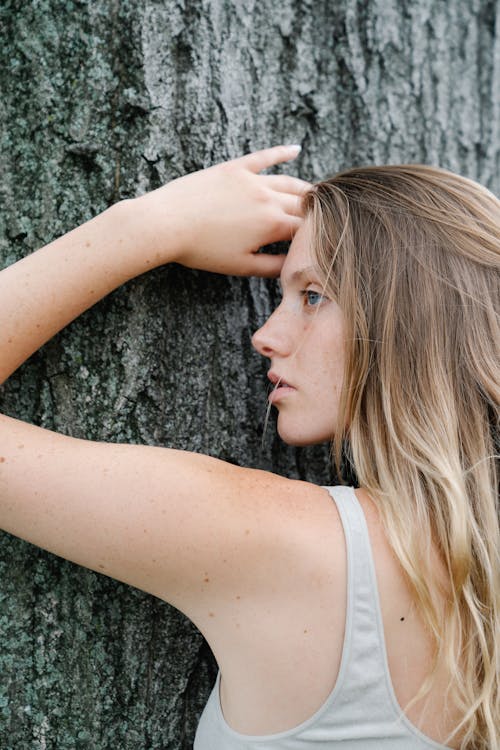 Close-Up Shot of a Woman Leaning on Tree Trunk