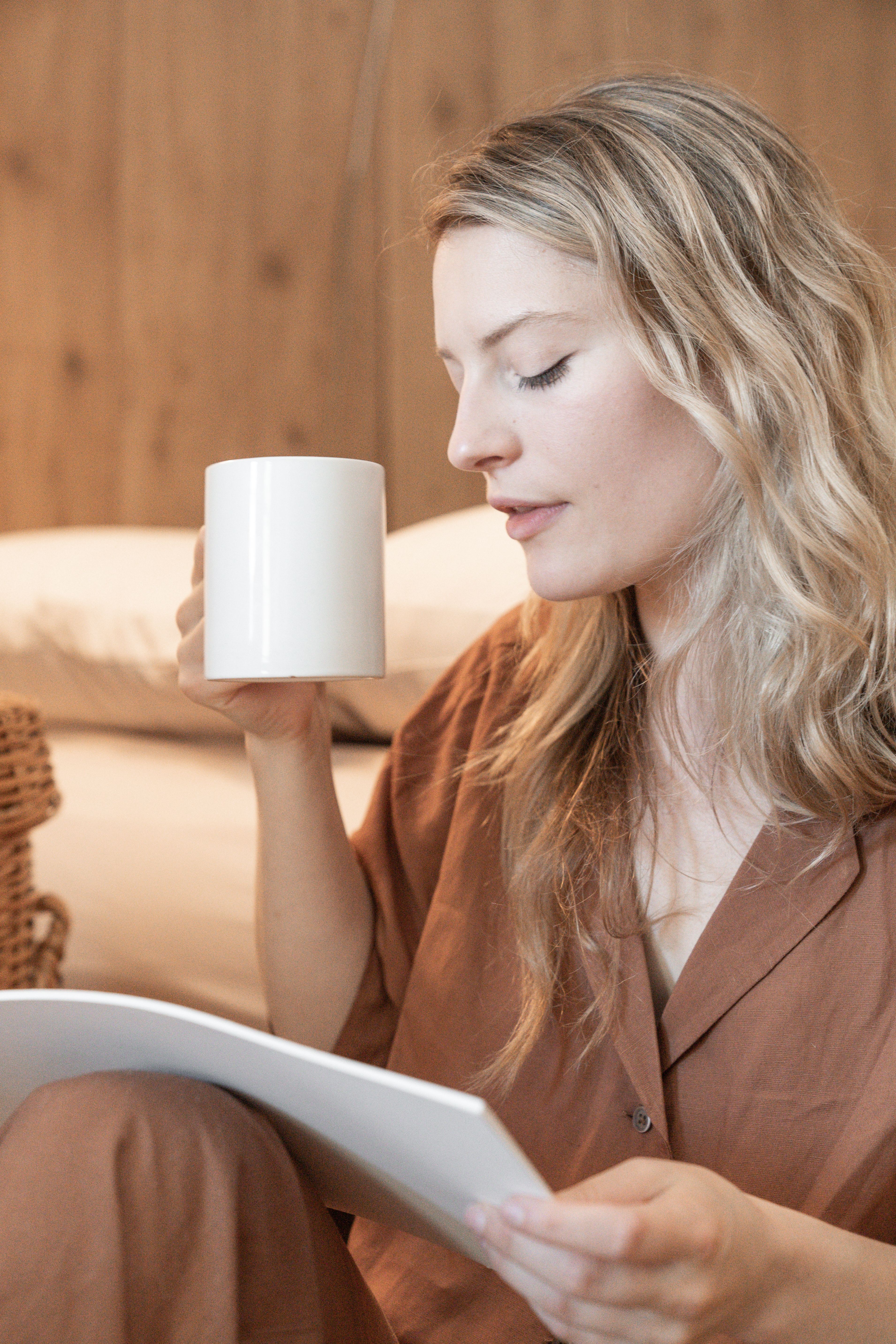 A serene moment with a woman enjoying coffee and reading at home.