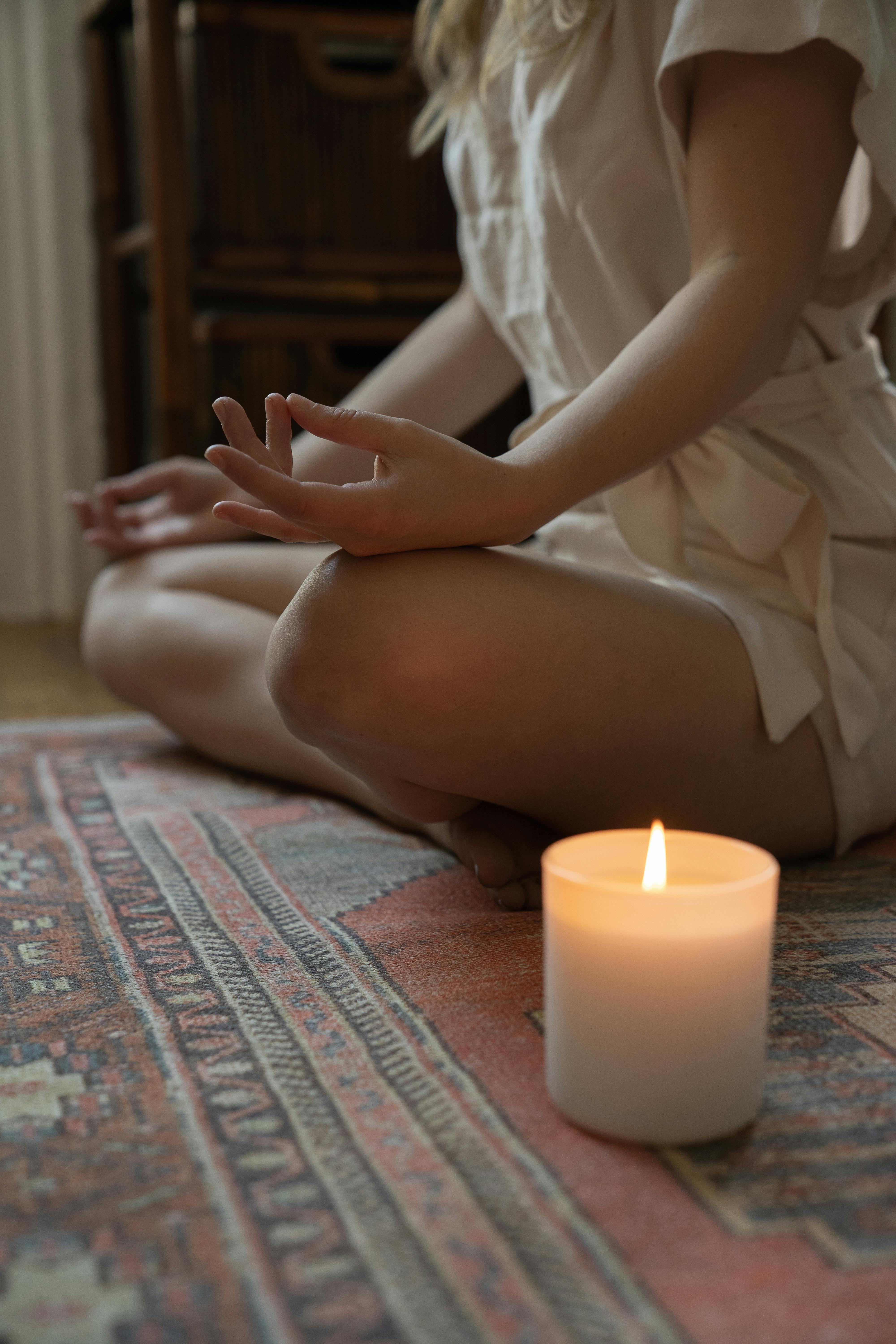 woman meditating next to a burning candle