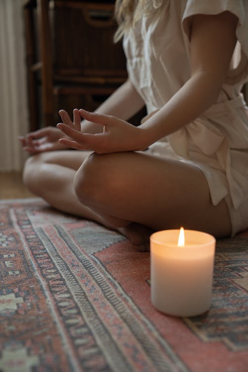 Free Woman Meditating Next to a Burning Candle  Stock Photo