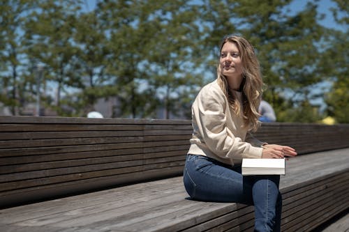 A Beautiful Woman Sitting on a Wooden Bench Looking Sideways